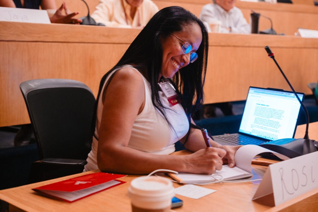 An audience member smiles while taking notes. 