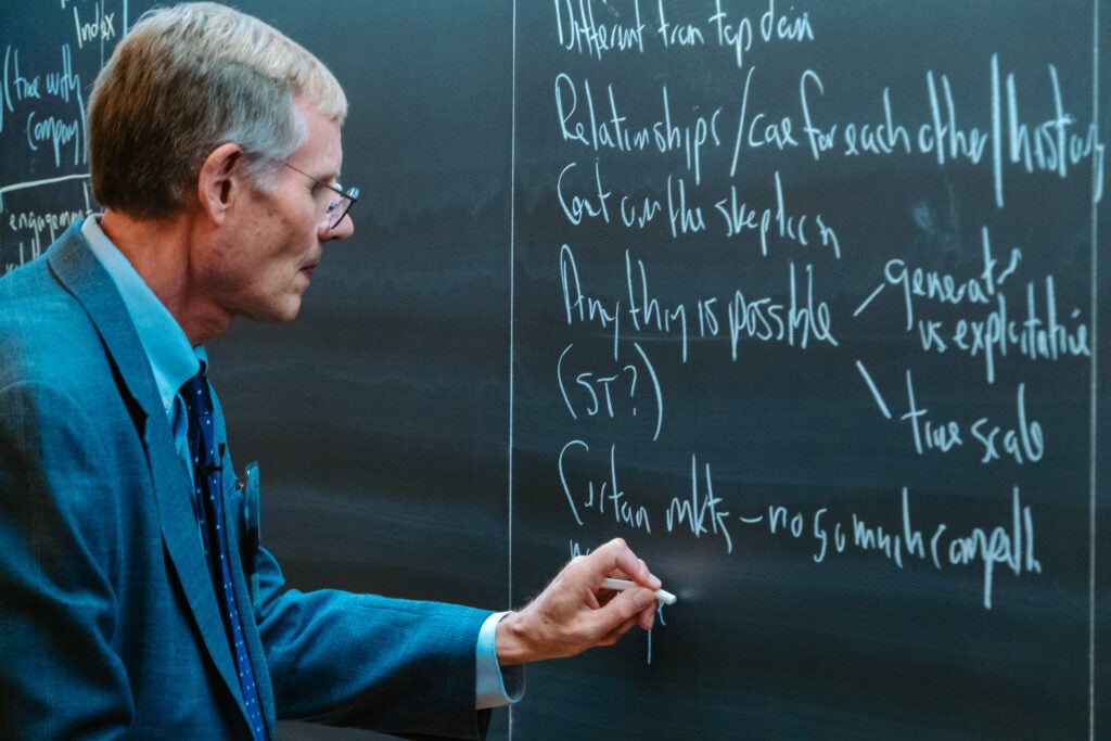 Professor Rick Siegrist writes on the chalkboard while presenting the case study "Happiness and Health: The Management Philosophy of Lee Kum Kee Group."  