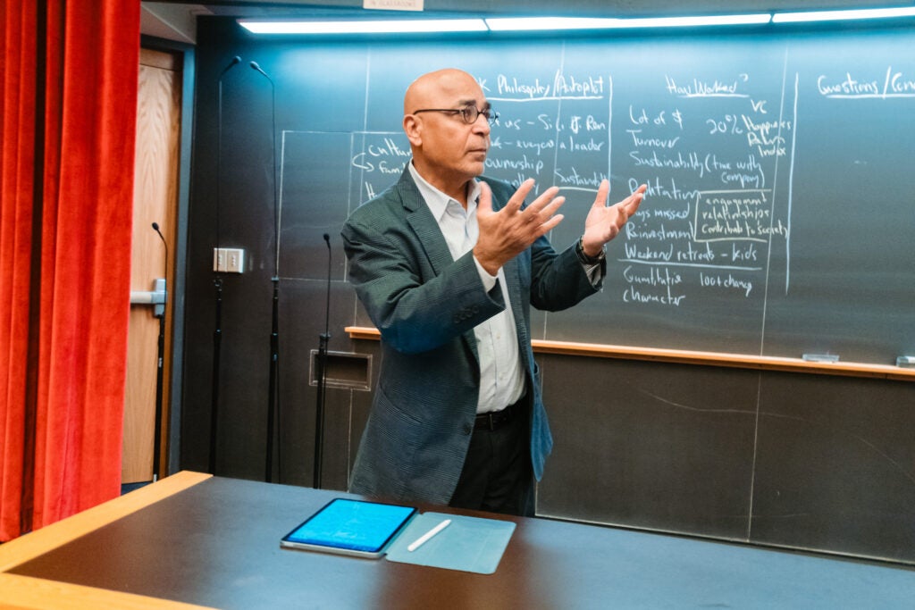 Vish Viswanath speaks in front of the chalkboard while presenting the case study on the Lee Kum Kee Group. 
