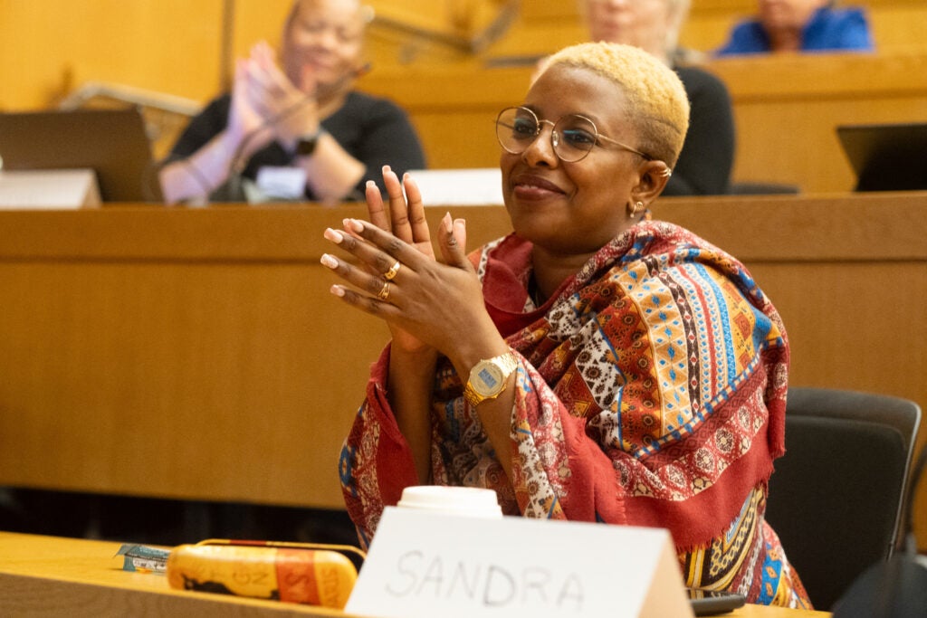 An alumnae in the audience applauds. 