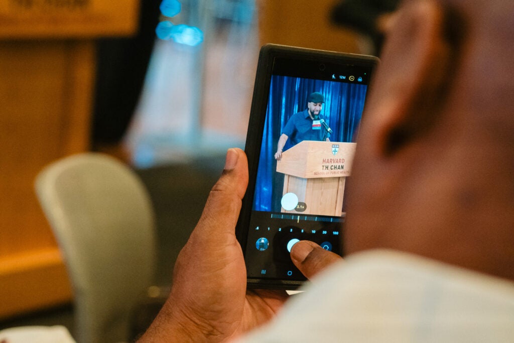 Eugenio Fernandez at the podium, seen in the phone camera of an audience member. 