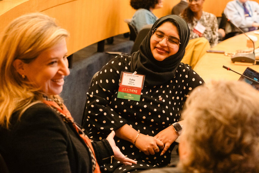 A group of alumnae trade smiles, with one wearing a reunion tag. 