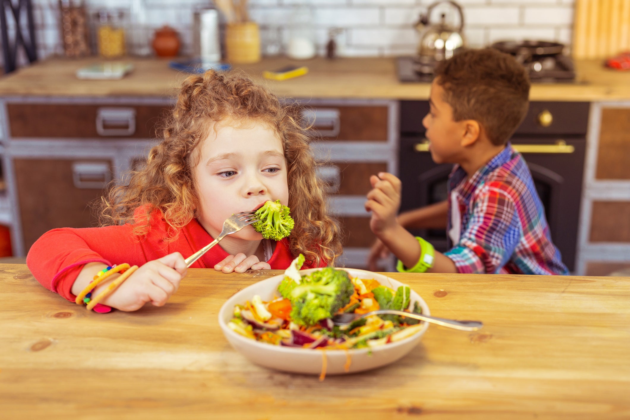 Girl at home eating broccoli