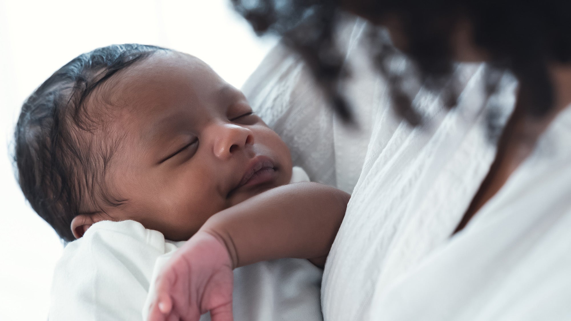 Close up portrait of African American baby lying in mother's arms