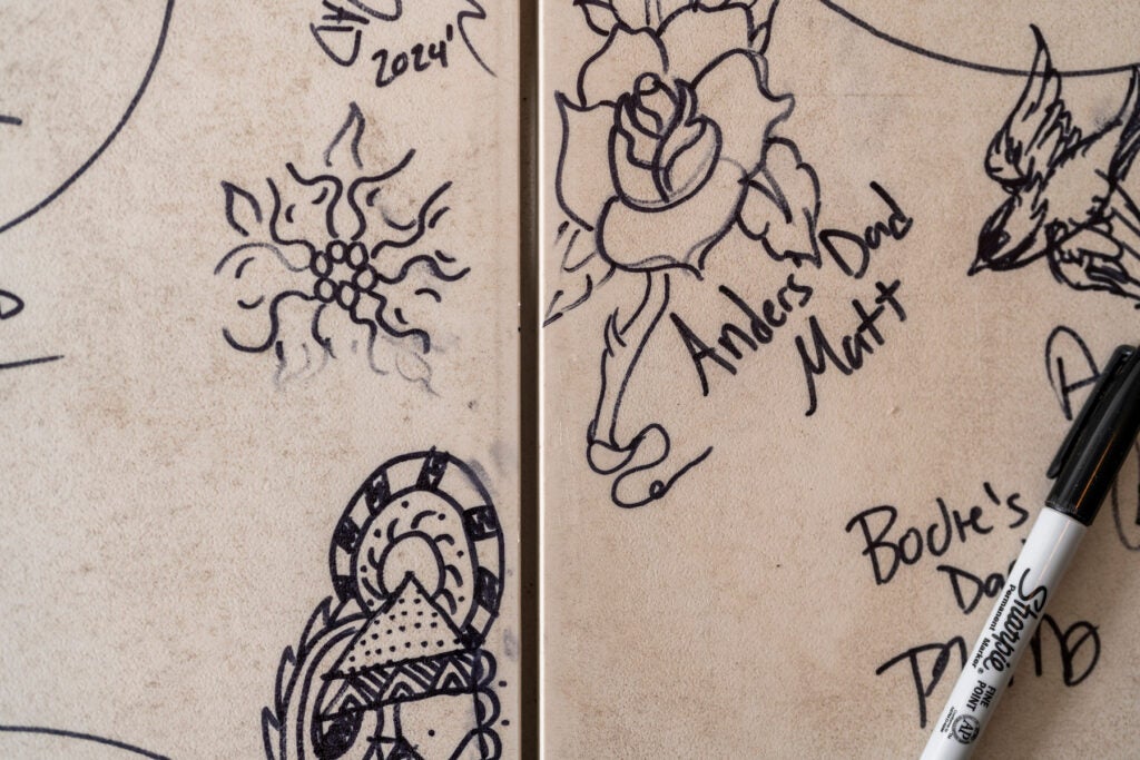 Detail of a white folding table with flowers, birds, and other doodles in sharpie.