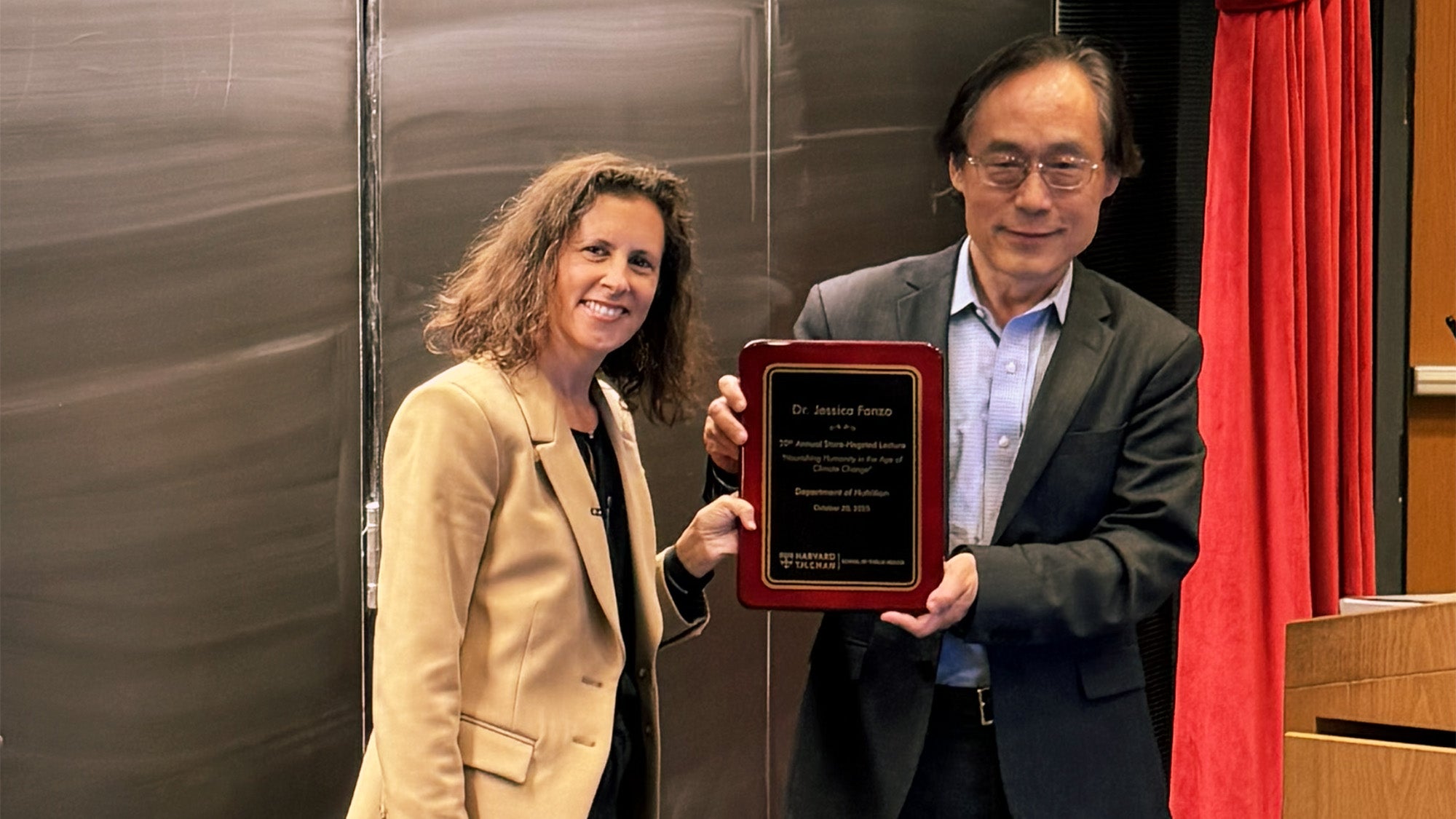 Jessica Fanzo with Frank Hu, chair of the Department of Nutrition. Hu holds a plaque.