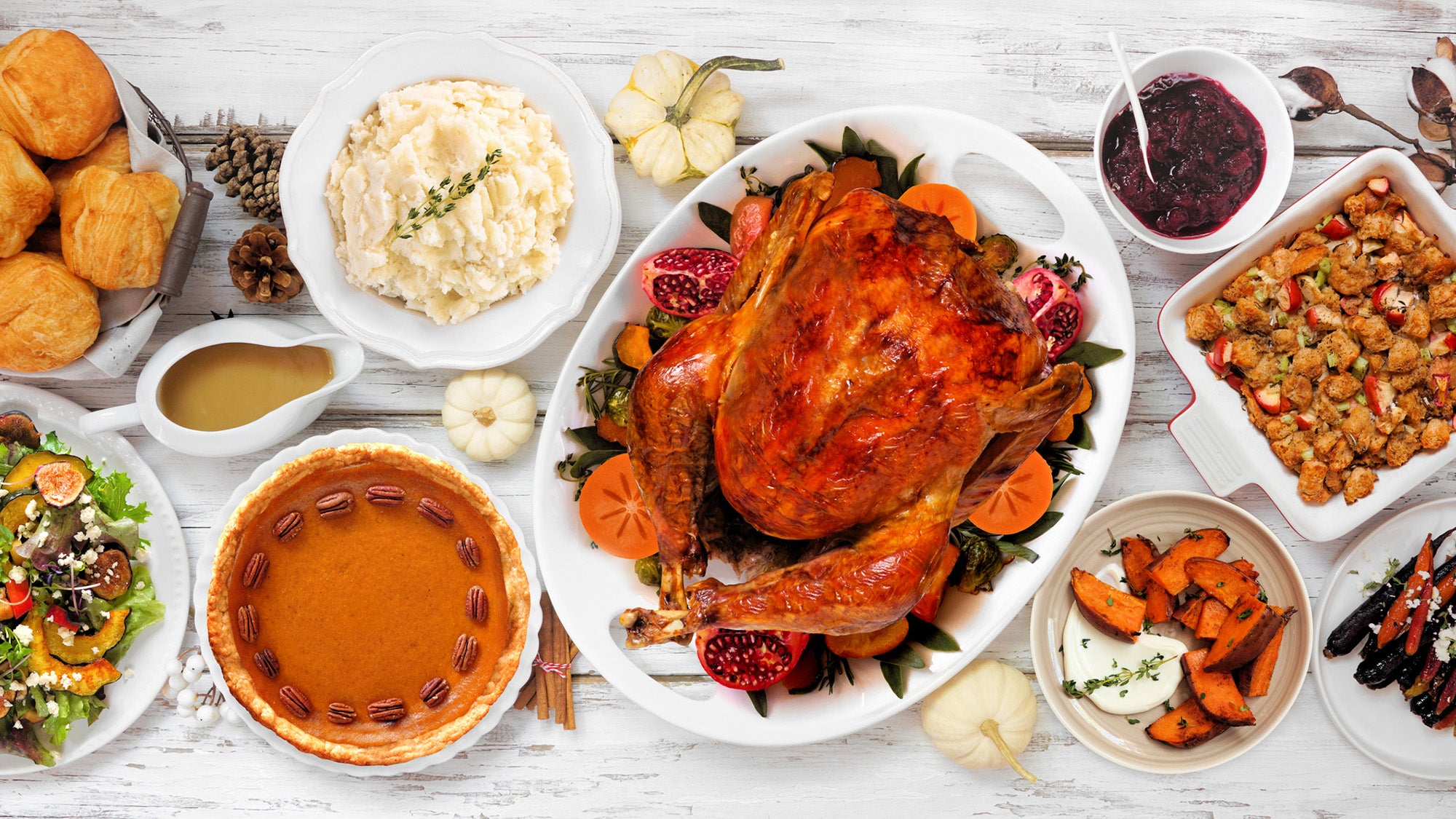 Thanksgiving turkey dinner. Above view table scene on a rustic white wood background. Turkey, mashed potatoes, stuffing, pumpkin pie and sides.