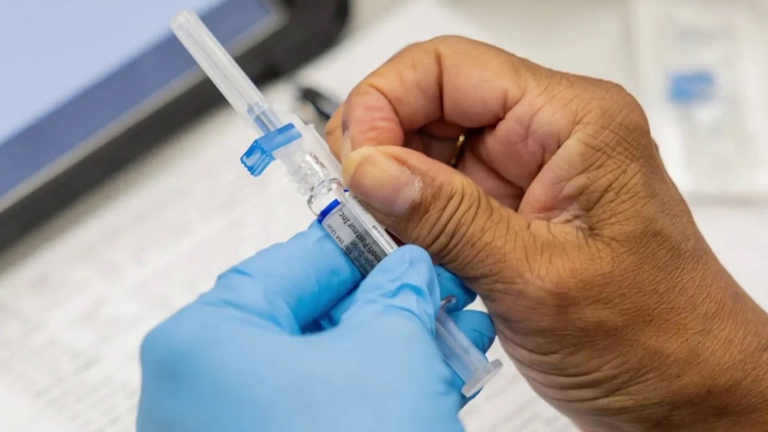 Person's hands preparing vaccine with syringe