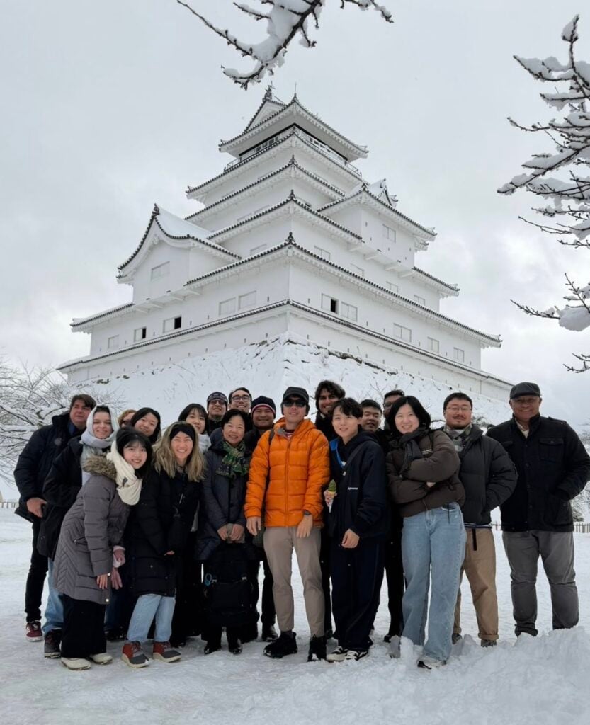 Students pose in front of a snowy building.