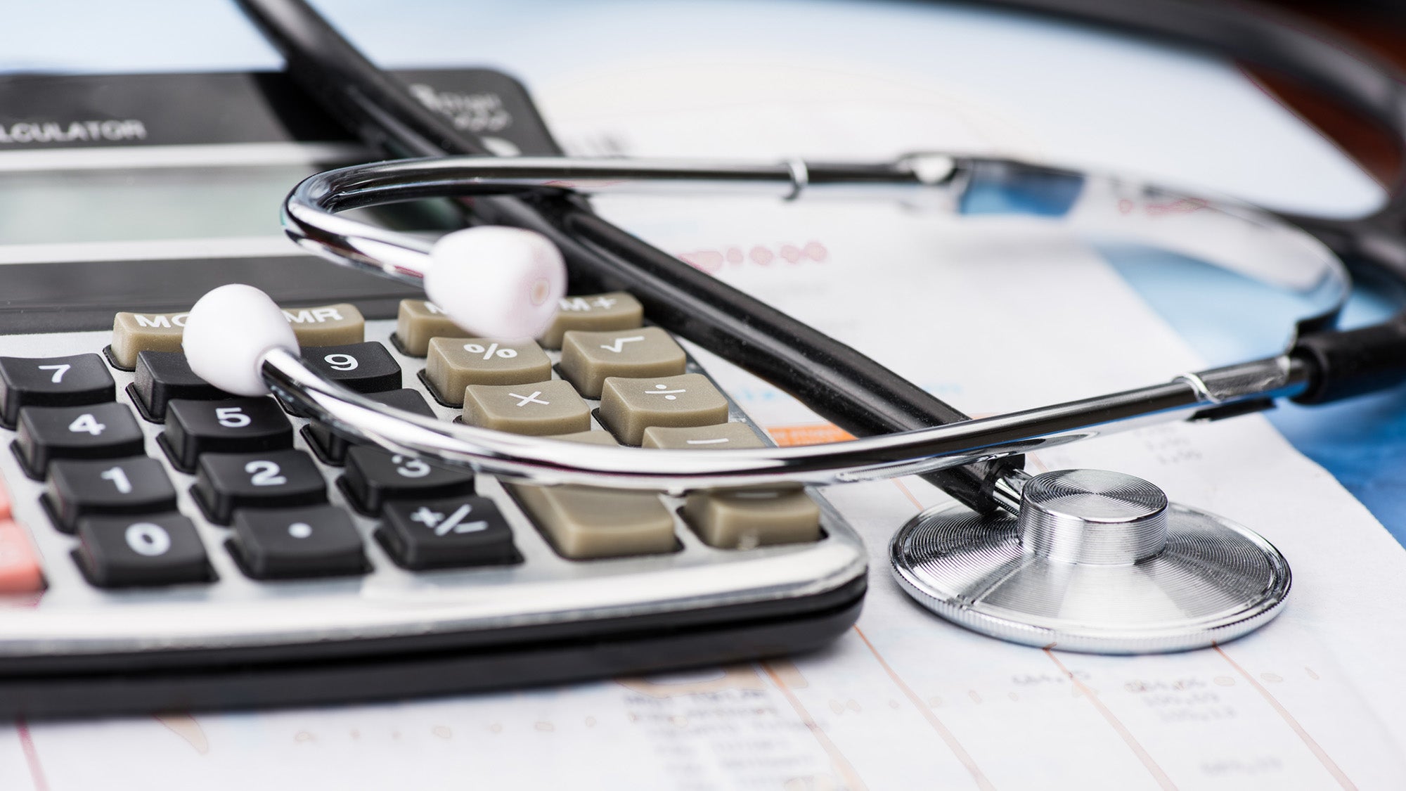 stethoscope and calculator on top of medical bill