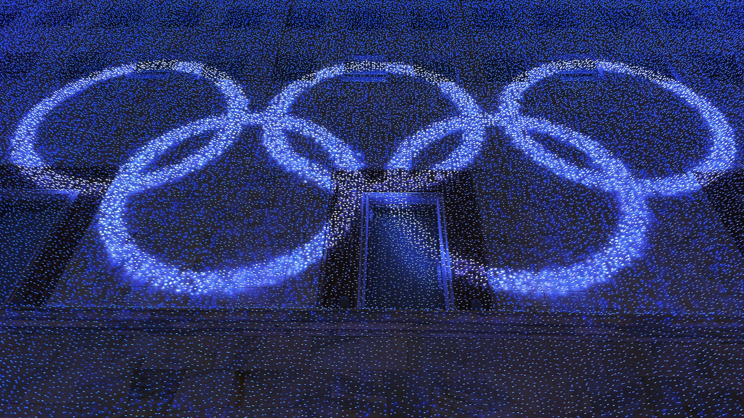 White light Olympic rings in night setting.
