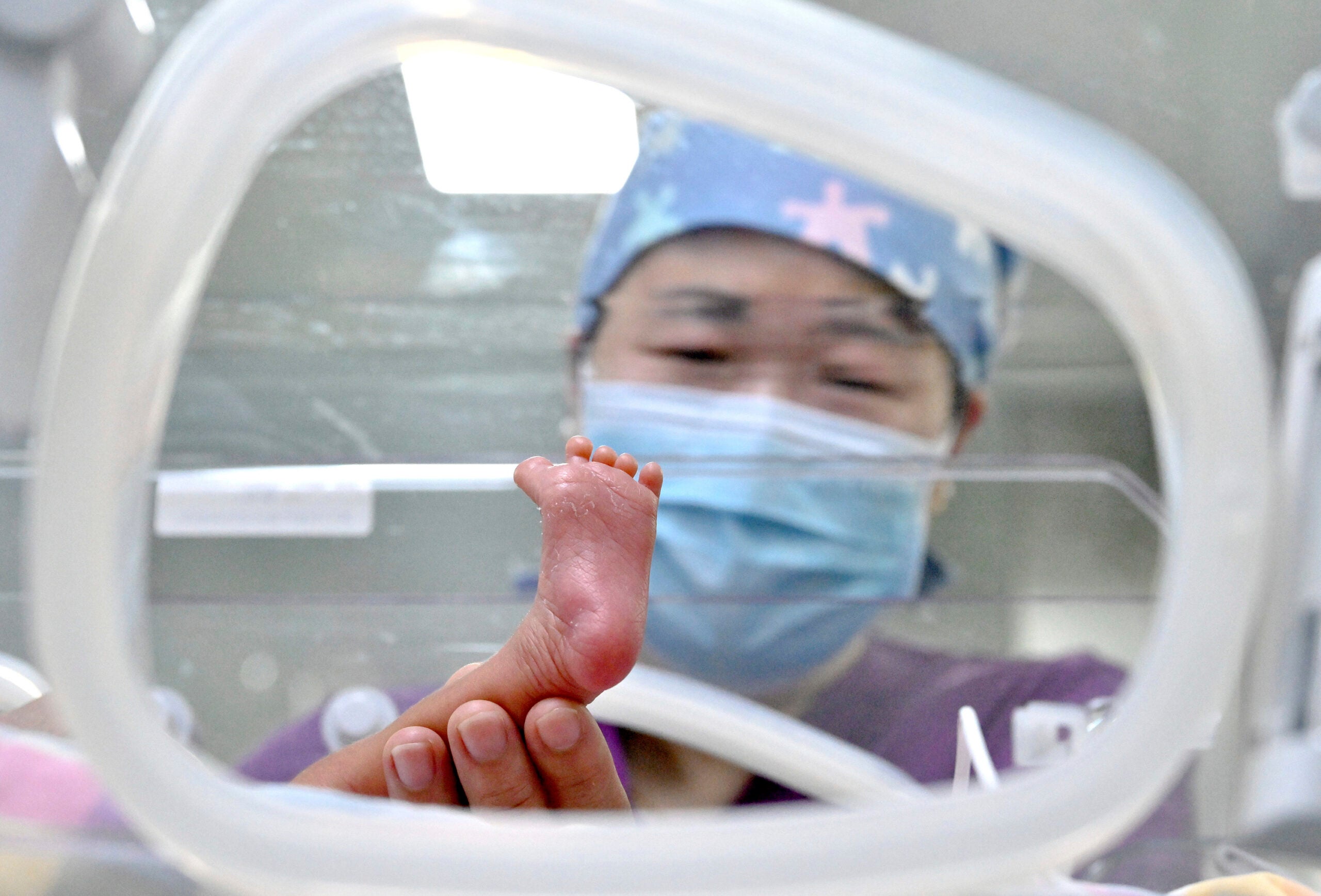 A nurse is giving a physical examination to a newborn in the neonatal intensive care unit.