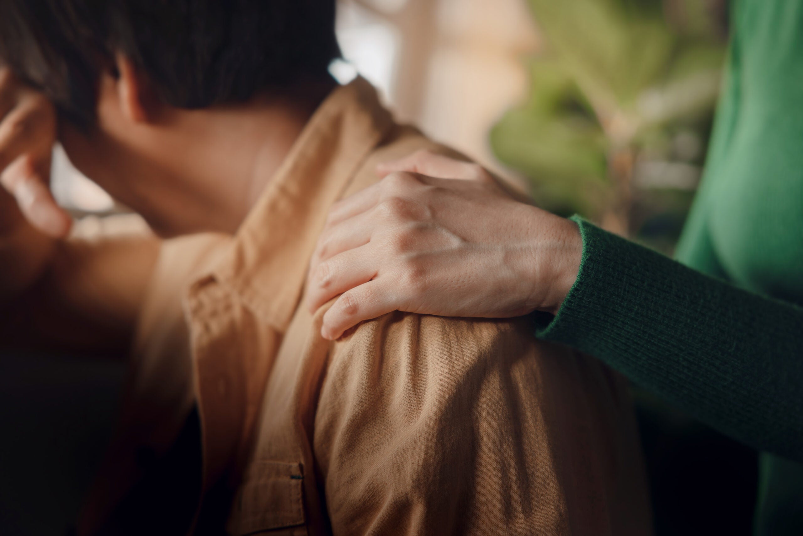 Close-up photo of someone's hand on another person's shoulder
