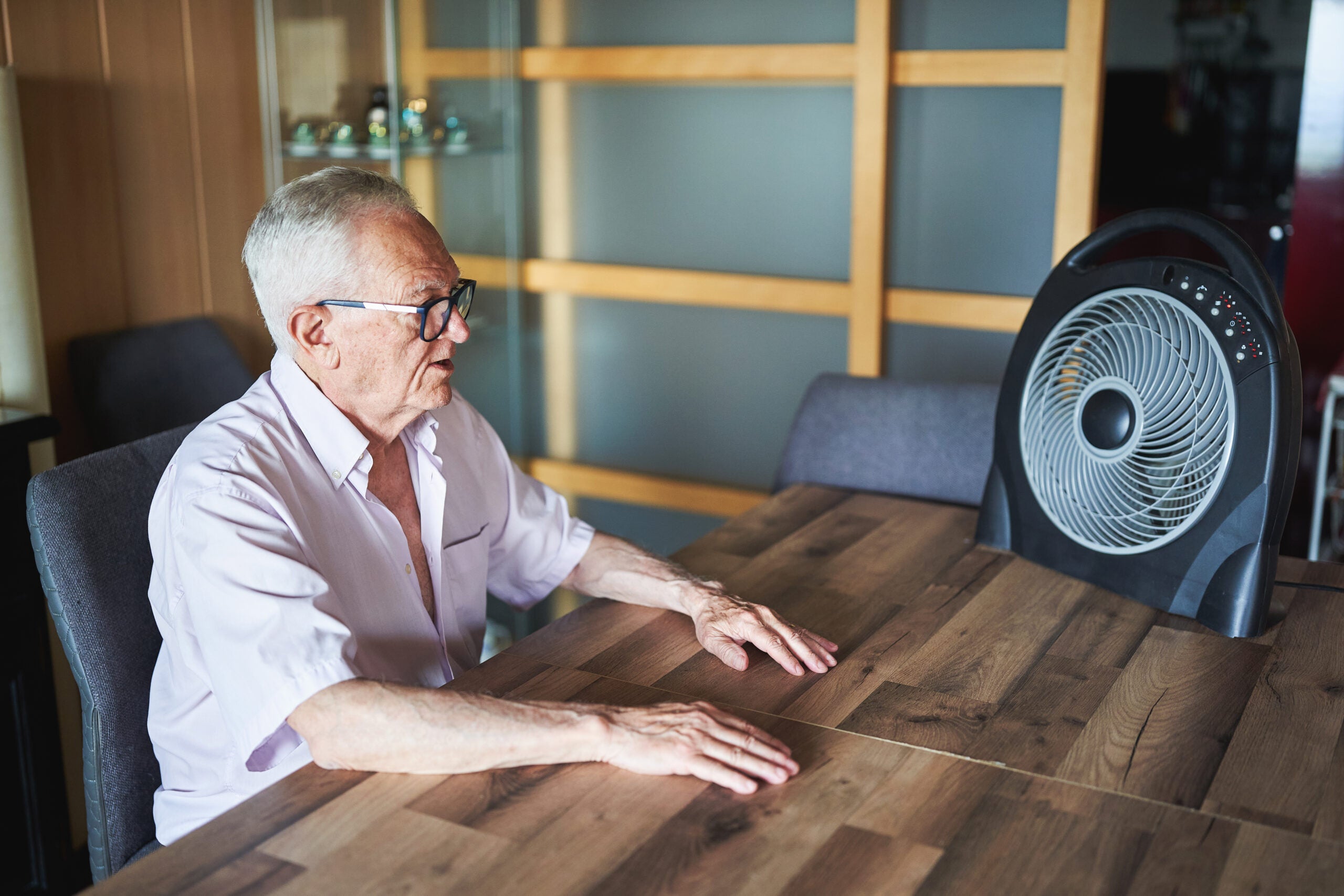 Man sitting at table with fan.