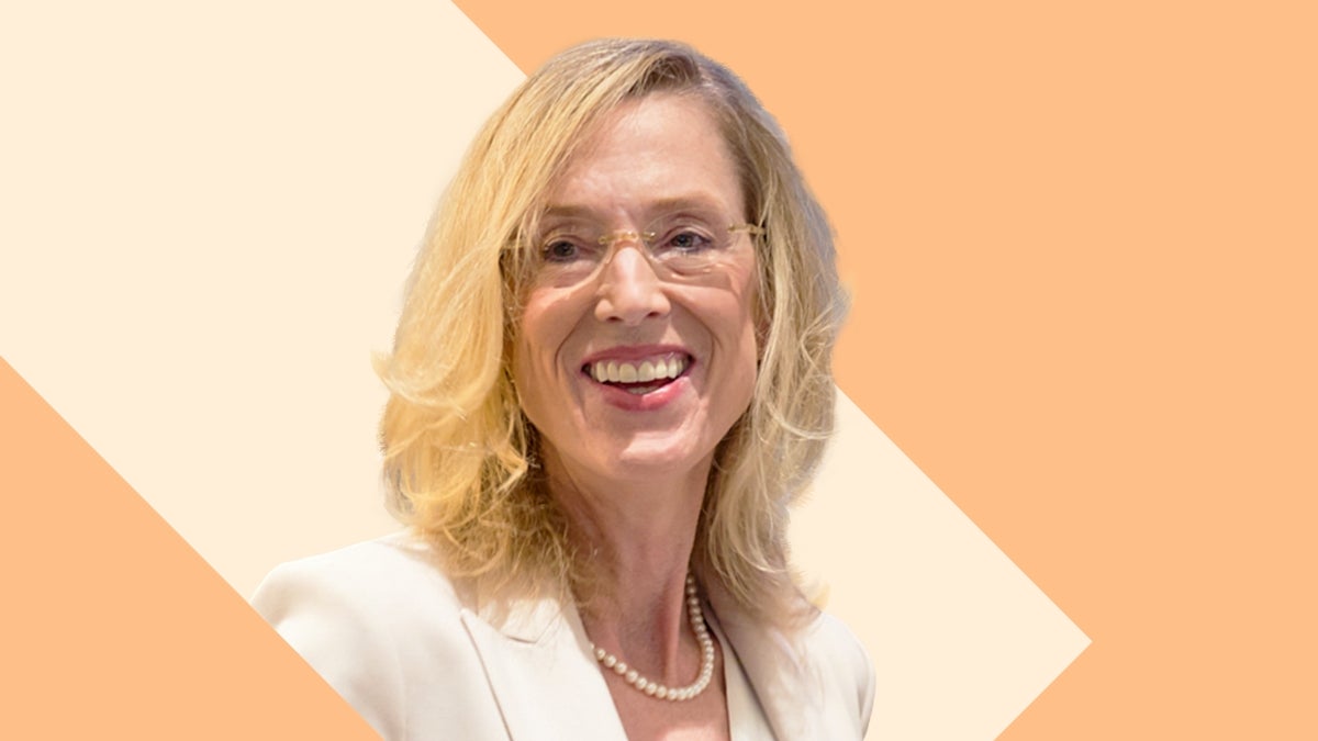 Headshot of Sue Goldie against a yellow and tan background