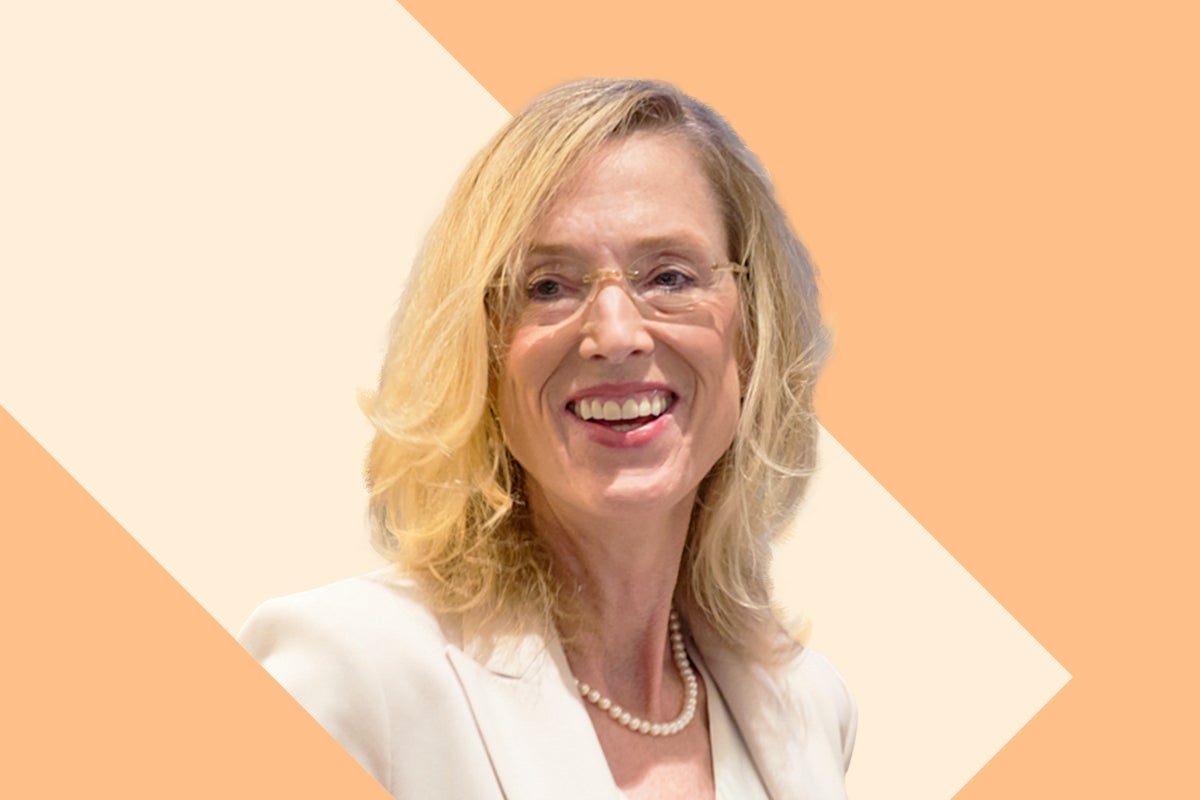 Headshot of Sue Goldie on a tan and cream background.