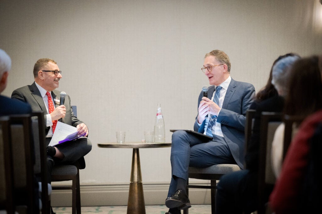 Dr. Massoud and Dean Baccarelli, seated at the front of the room and speaking animatedly. 