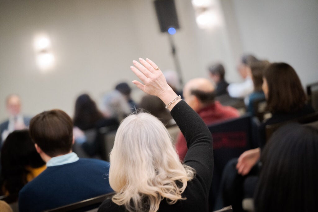 An audience member raises her hand to speak. 