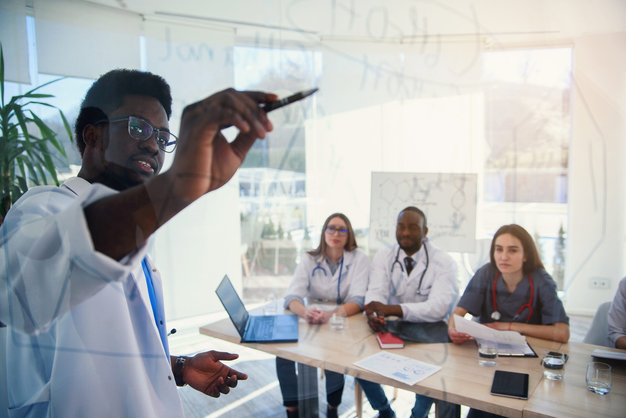 Doctor writing on board some formulas for interns in a conference room at a hospital