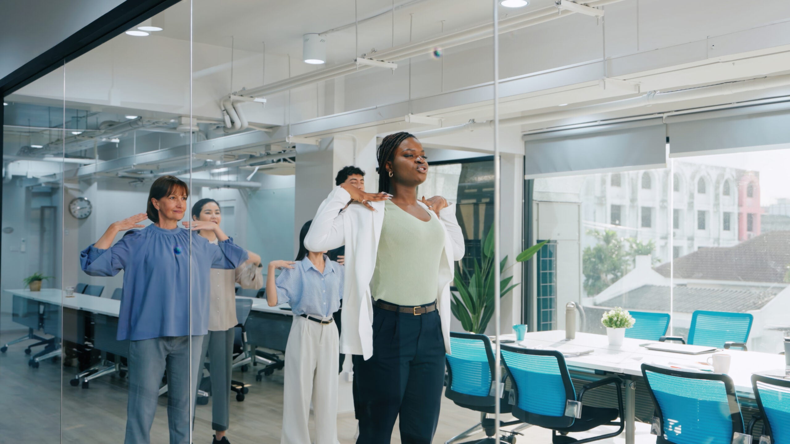 Professionals engage in stretching exercises to improve workplace health, reduce stress, and foster teamwork in a corporate environment.