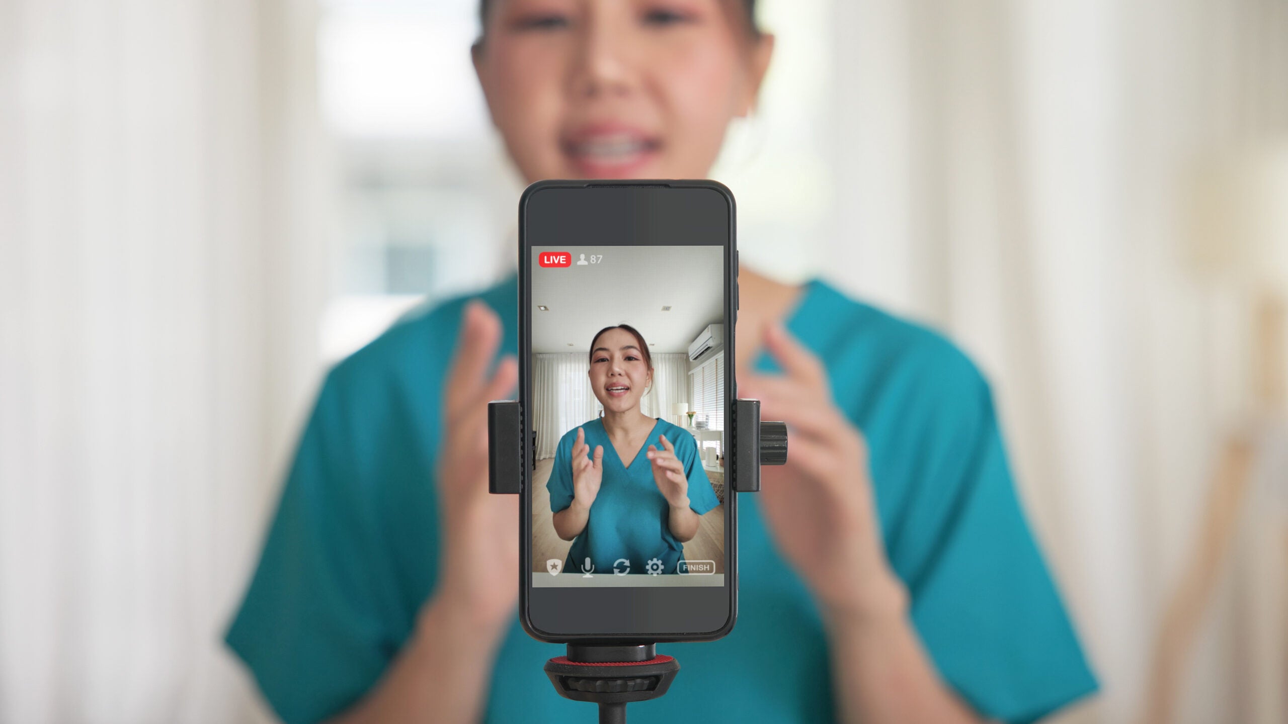 Nurse standing in front of an iphone attached to a tripod livestreaming