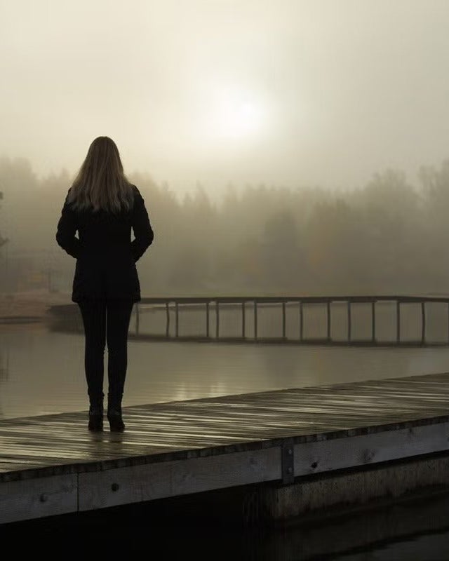 Woman standing on foggy dock