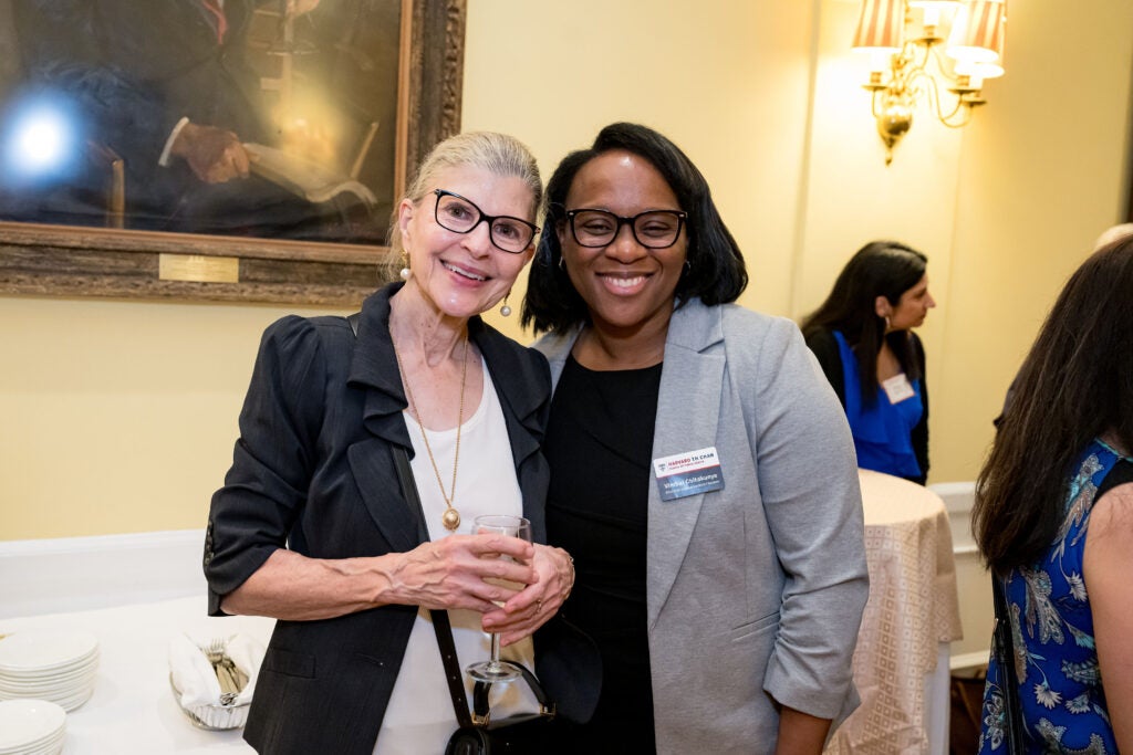 Harvard Chan staff member Vimbai Chitakunye poses with a blonde guest wearing glasses and holding a glass of white wine.