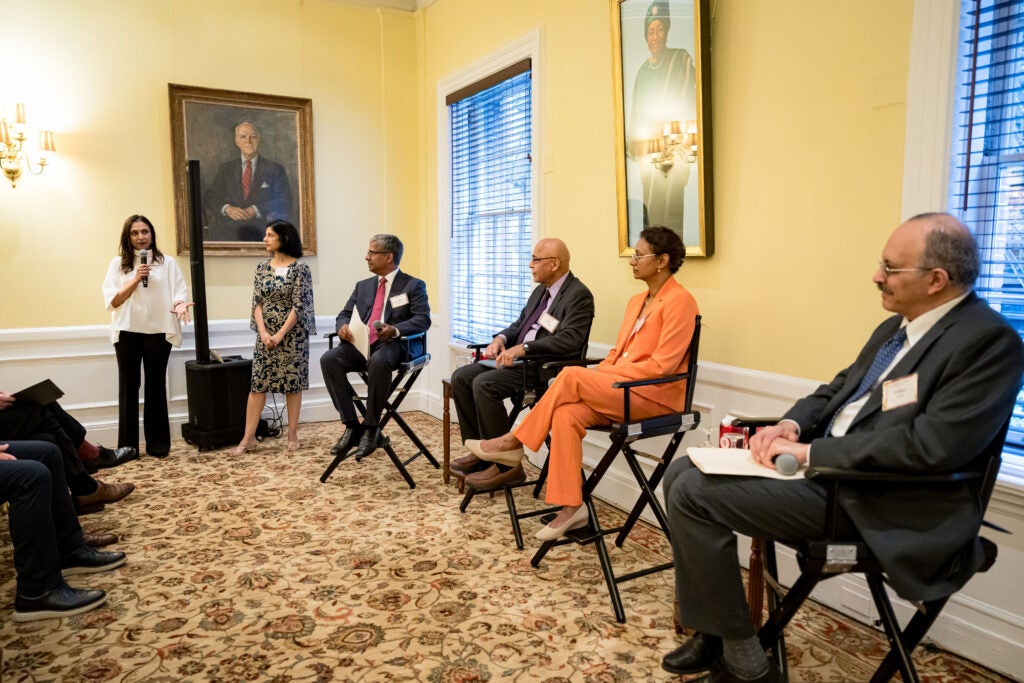 Padmini Sekhsaria introduces the panel while fellow co-host Sheila Sarma, and the four seated panel members, watch.