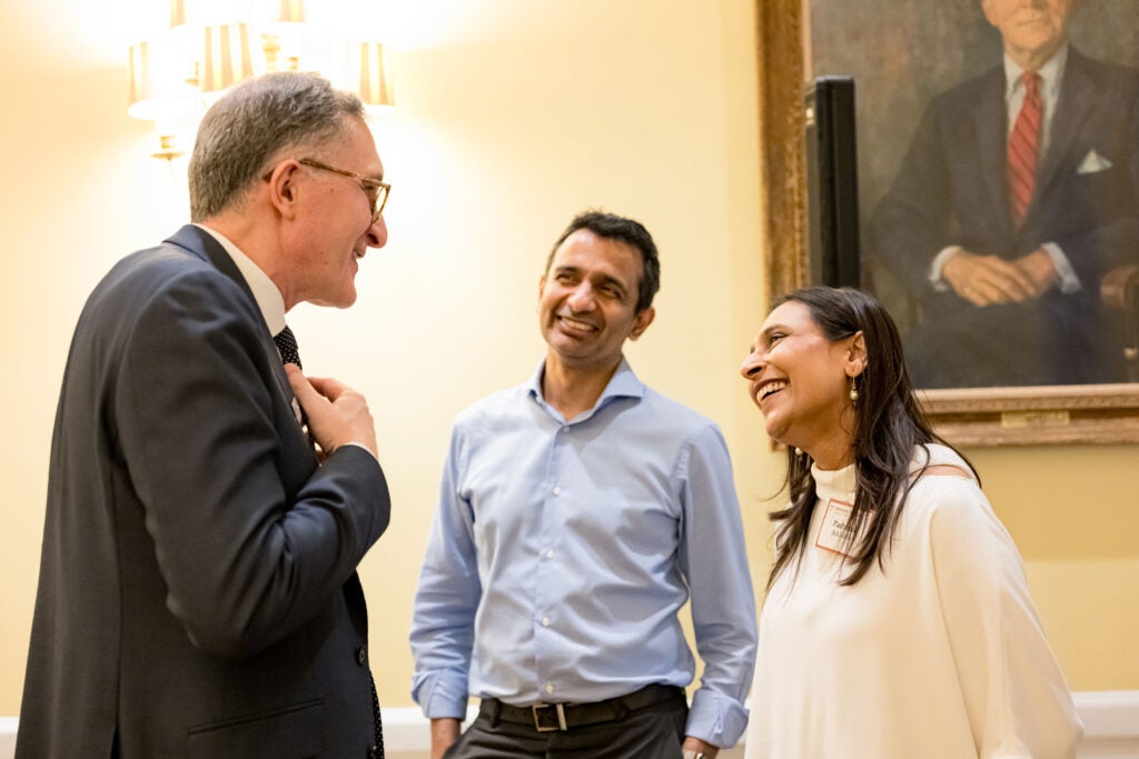 Dean Andrea Baccarelli, Padmini Sekhsaria, and another guest wearing a blue dress shirt laugh while conversing together.
