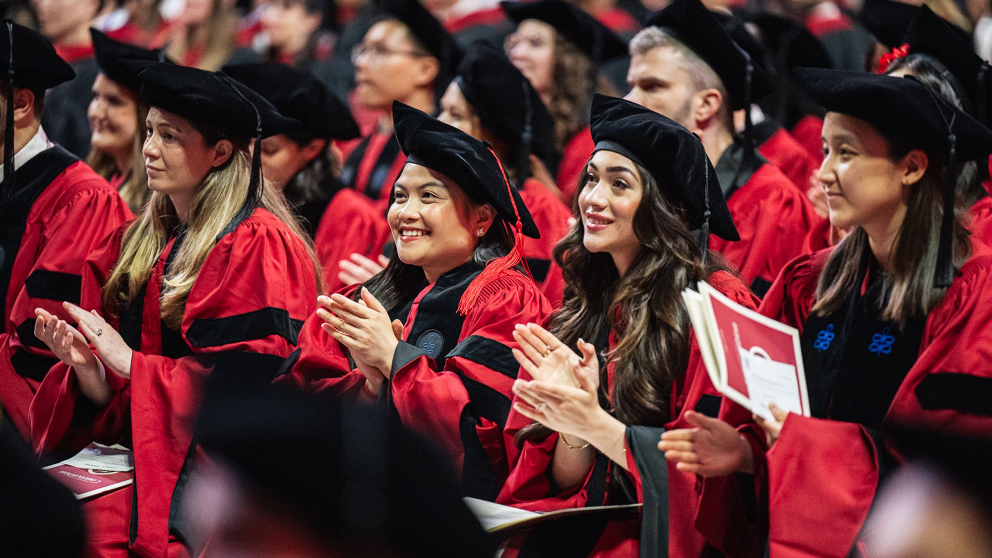 A row of smiling graduates applaud