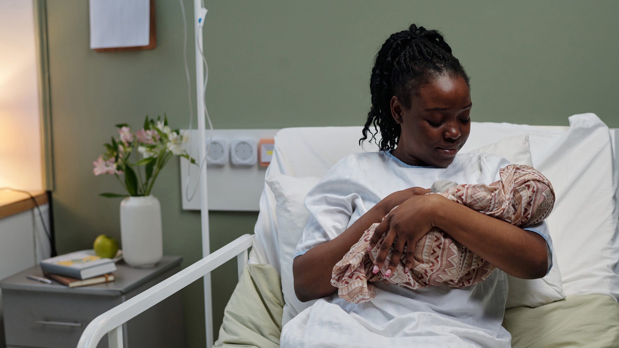 A mother lying in a hospital bed holding her newborn