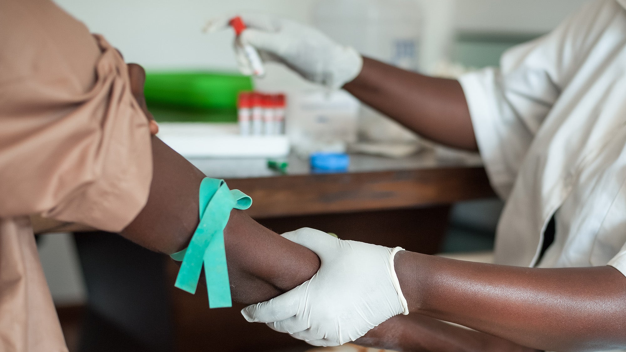 A nurse holds a man's arm as she prepares to draw blood