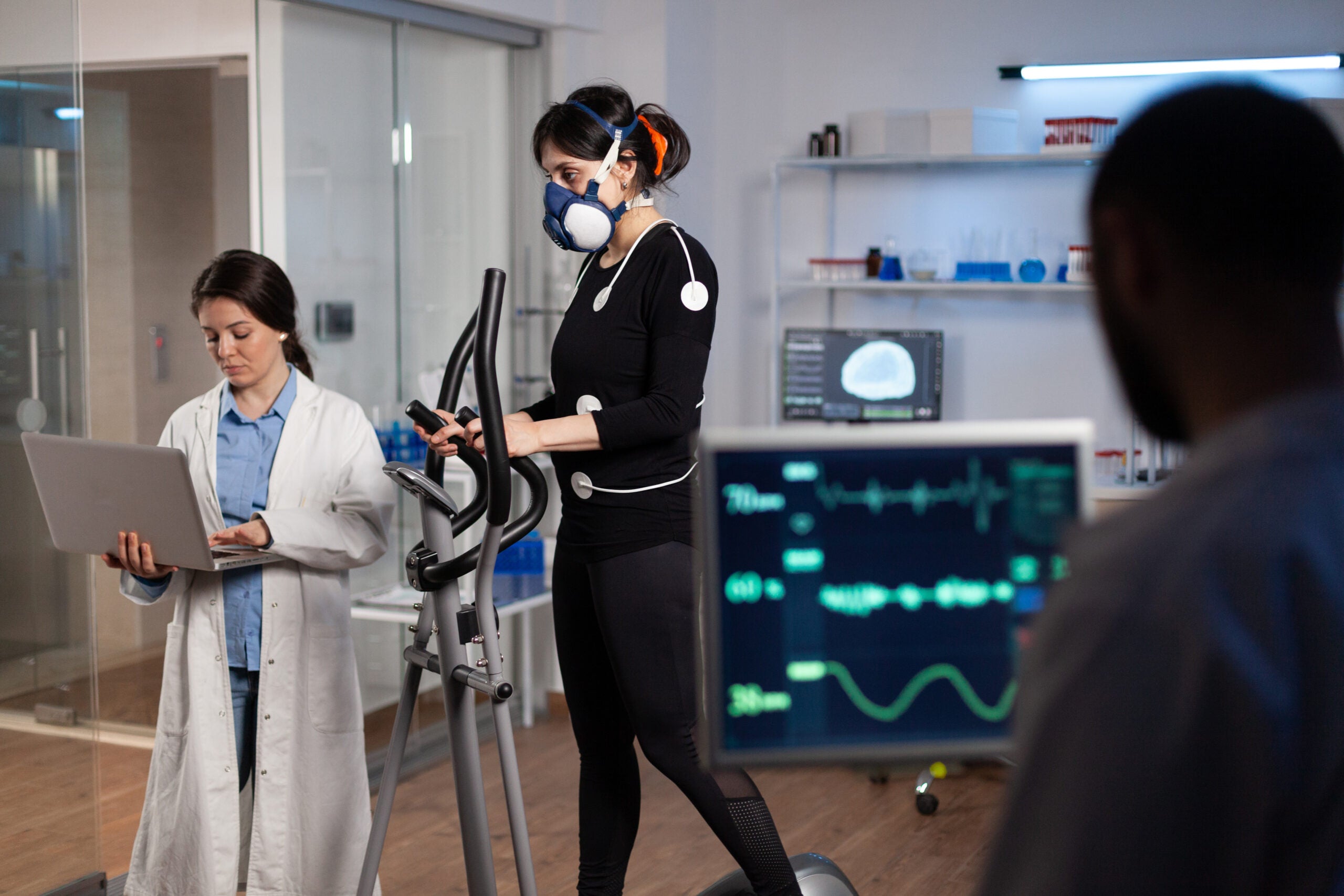 Athlete sportwoman with electrodes attached to her body running on cross trainer
