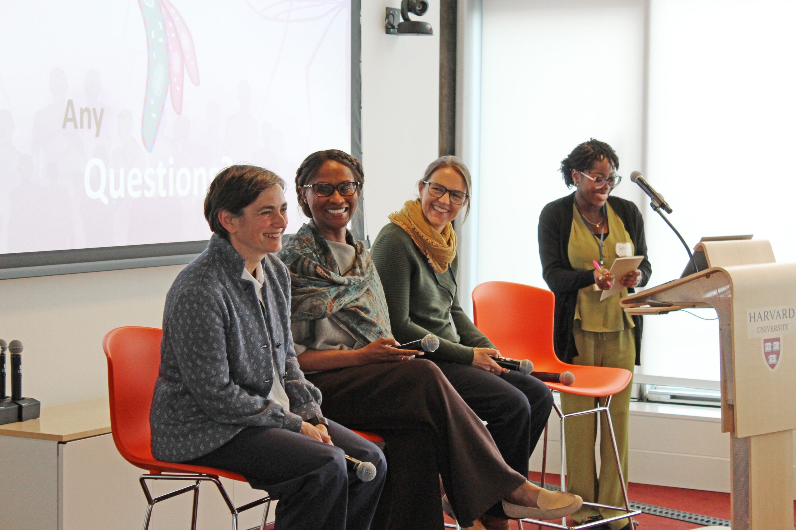 Malaria researchers Flaminia Catteruccia, Azza Idris, and Caroline Buckee answer questions after their symposium talks. The three sit in a row of chairs smiling and laughing.