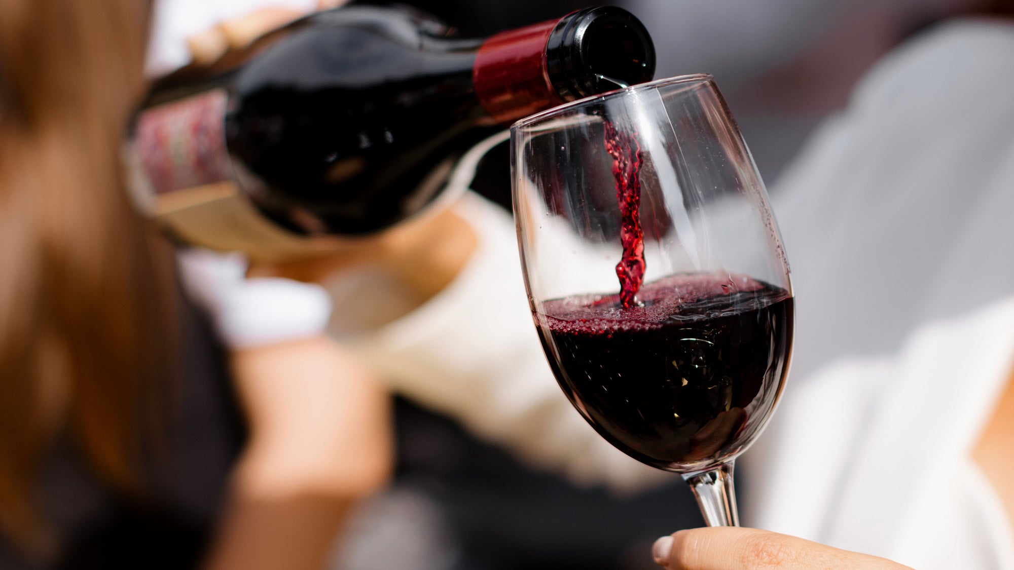 Close-up of a person pouring red wine into a glass