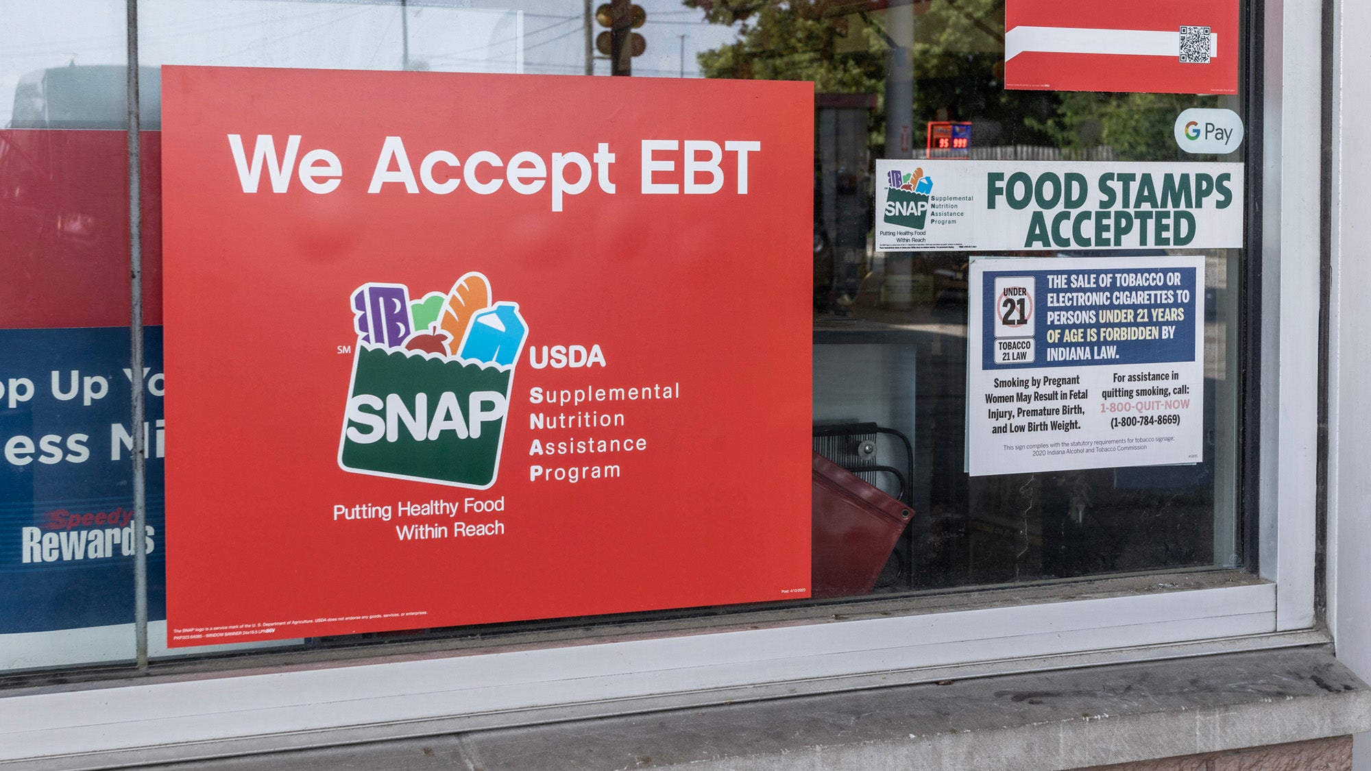 A sign in a grocery window with SNAP logo and "We accept EBT"