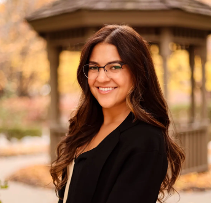 Sarah Rahal is pictured from the waist up in a black blazer and black glasses