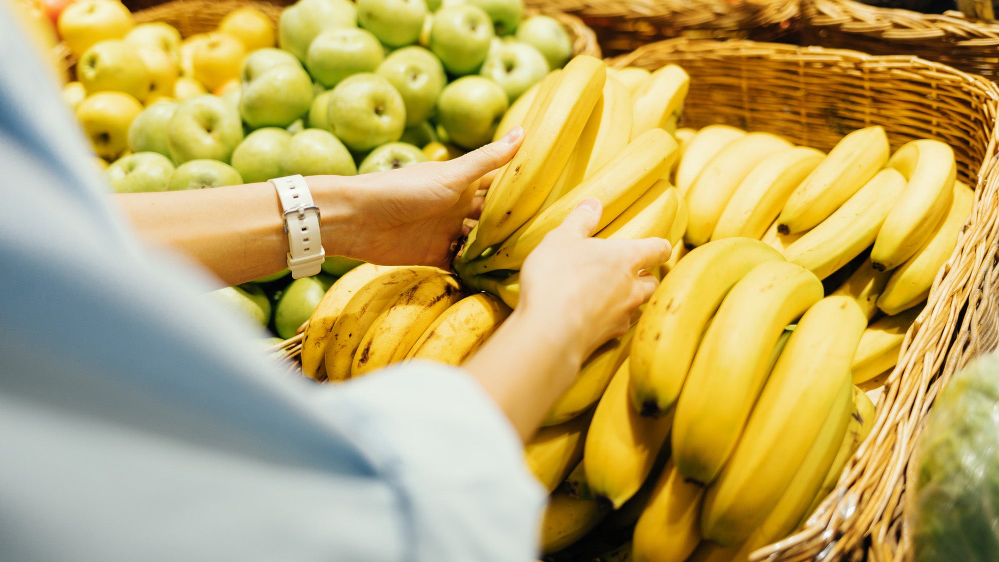 Close-up on hands of woman buying bananas in grocery store
