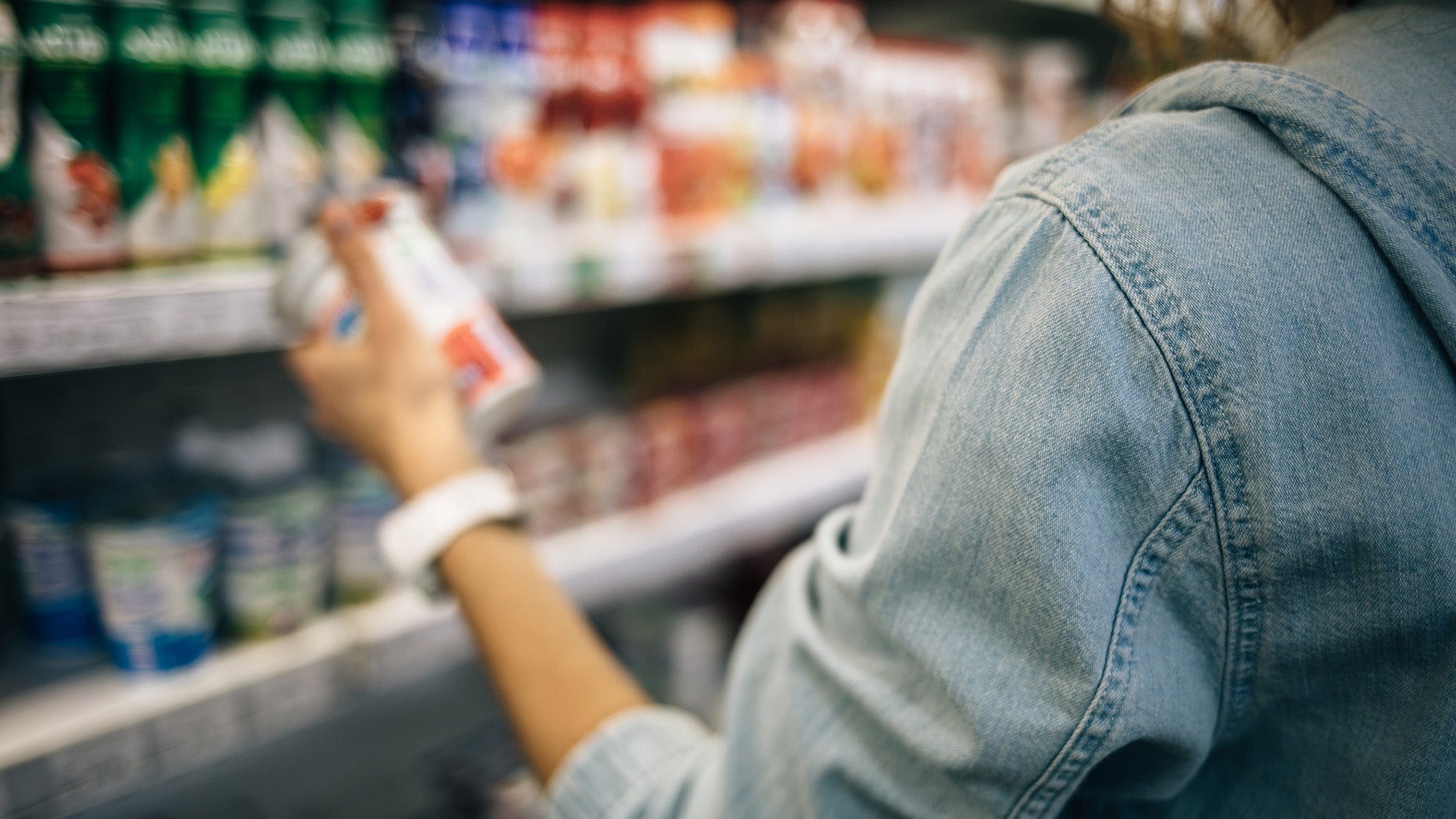 Close-up on hand of woman reading the label of a can in a grocery store