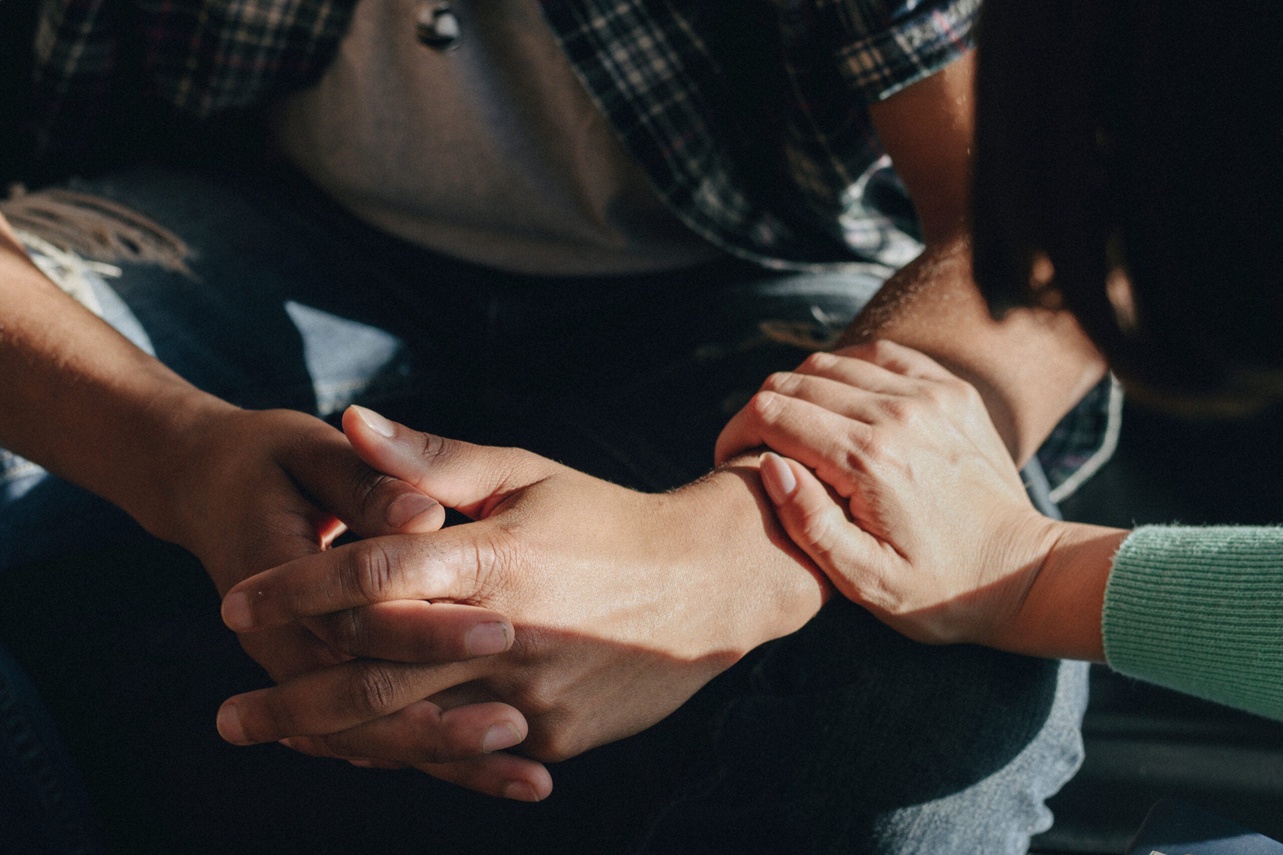 A womans hand holding a man's wrist in a comforting way.