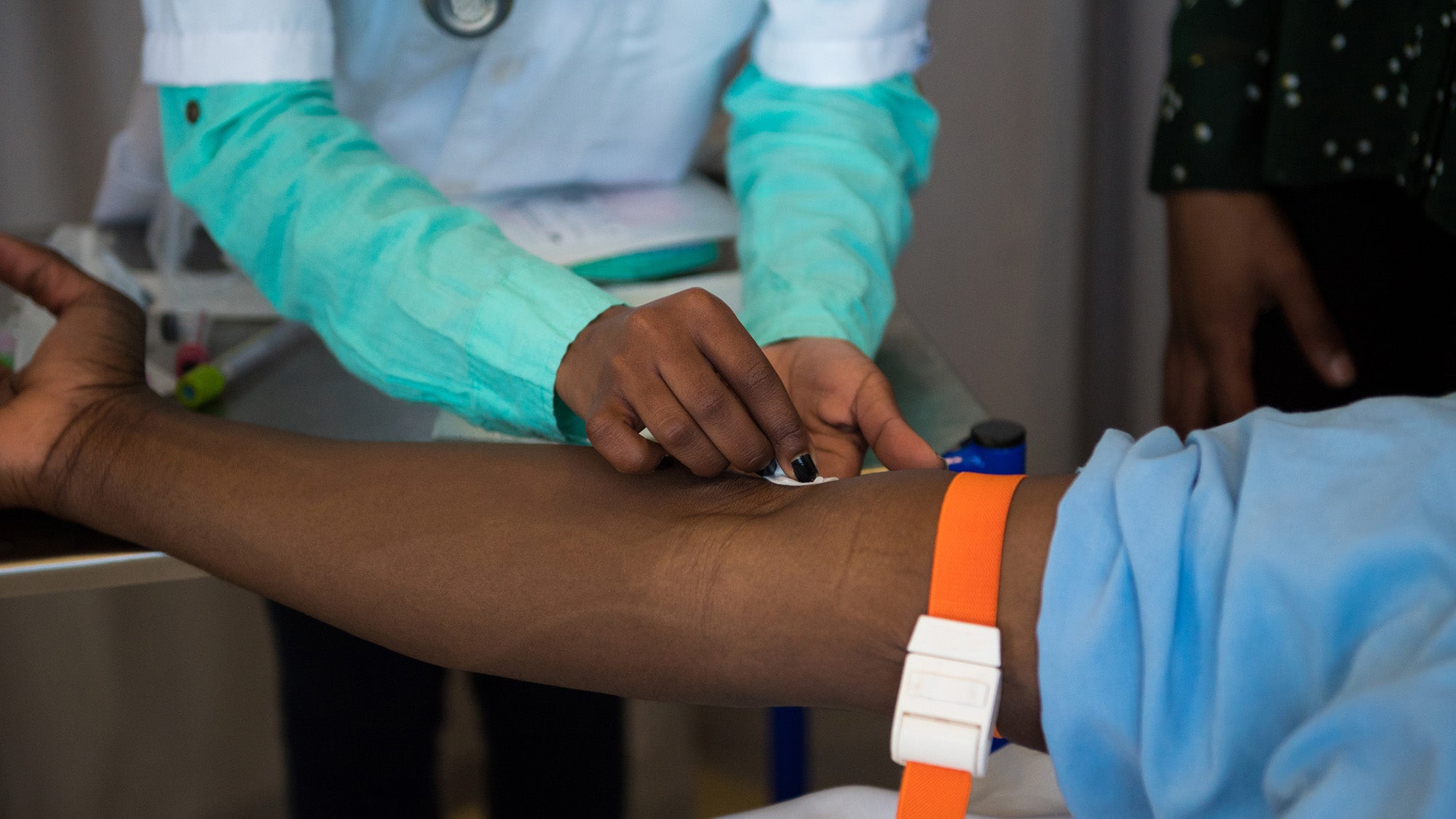 Hands of a health care worker drawing blood from patient's arm