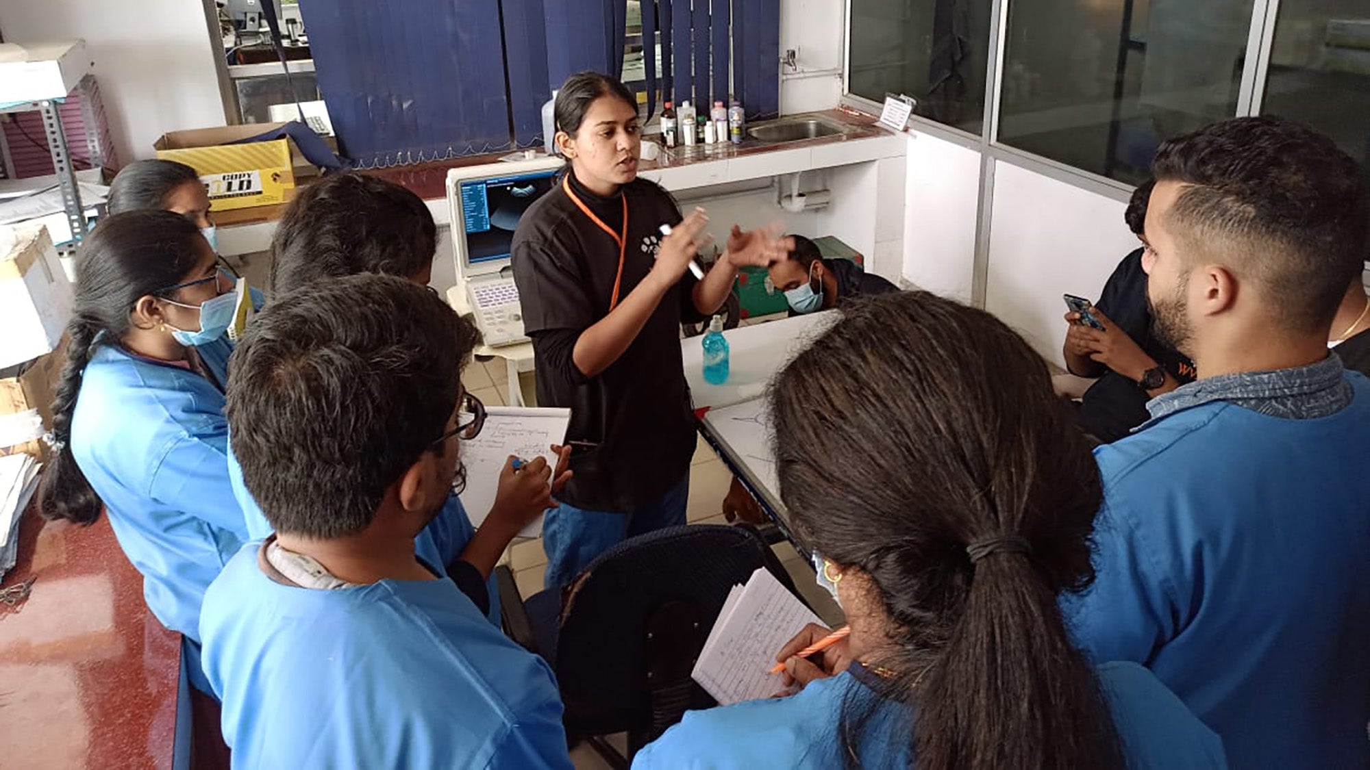 Shruti Gogia speaks with a group in medical scrubs