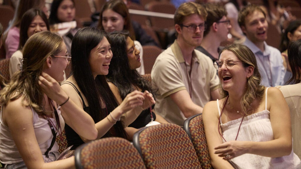 Students in an auditorium chat and laugh