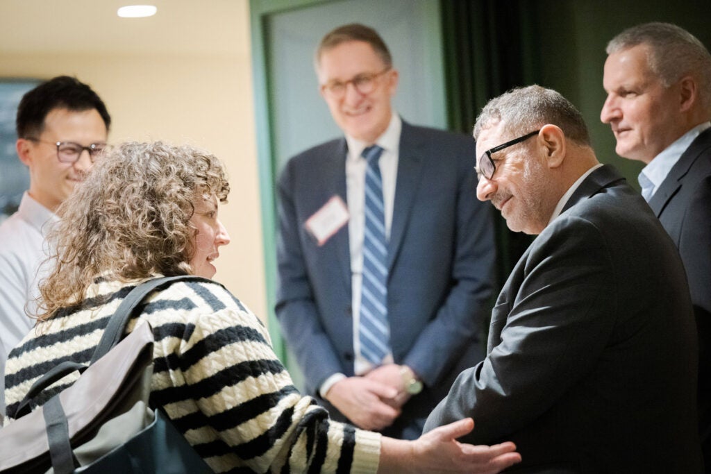 Rashad Massoud greets a woman while Dean Baccarelli and other events guests smile. 