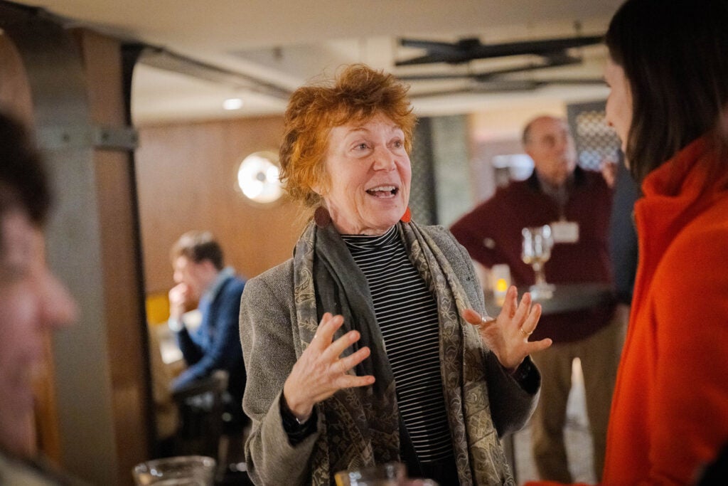 A woman conversing with her hands in motion at a happy hour.