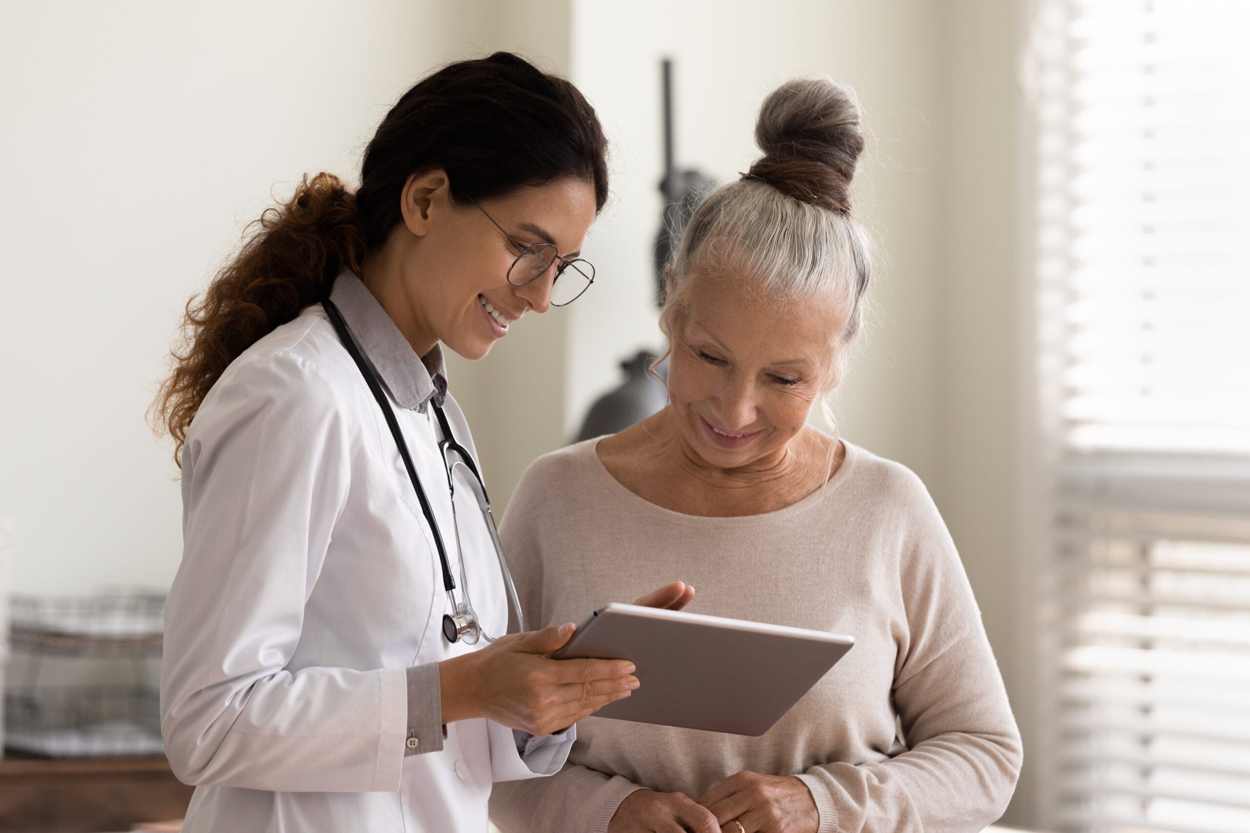 Female doctor is looking at an iPad and her elderly patient