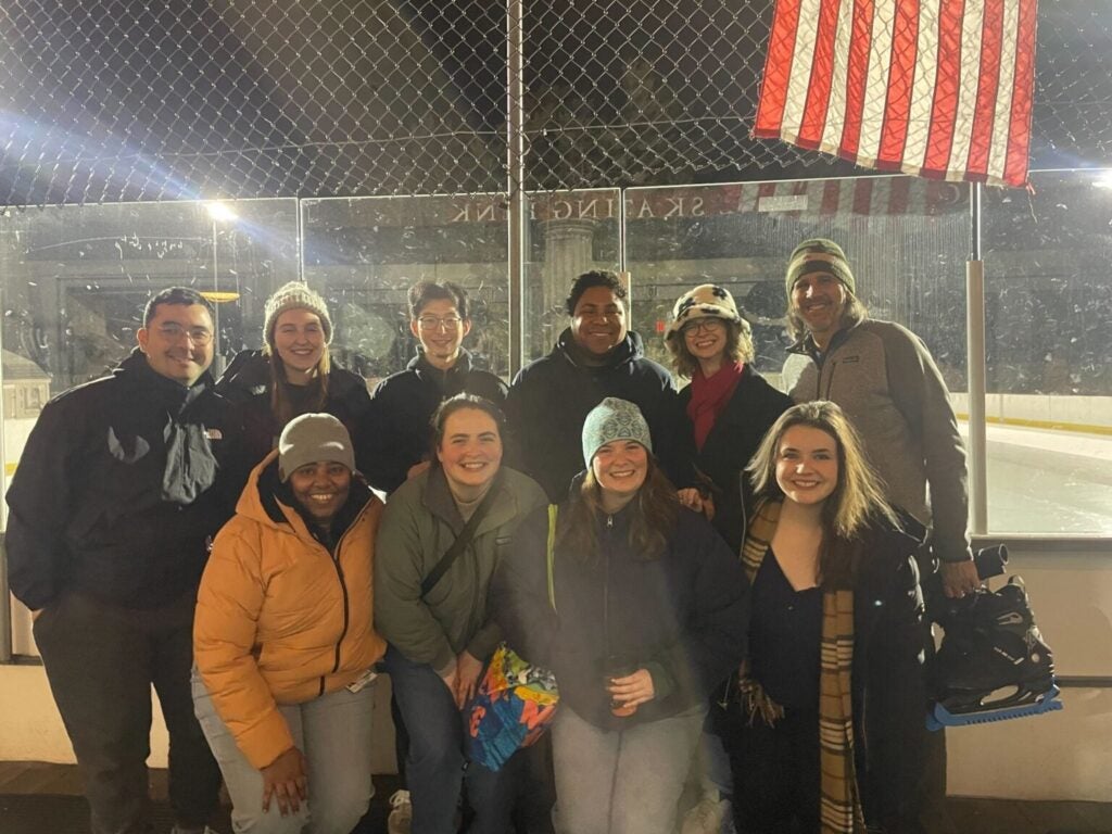 The Dvorin Lab group standing before an outdoor ice skating rink at night.