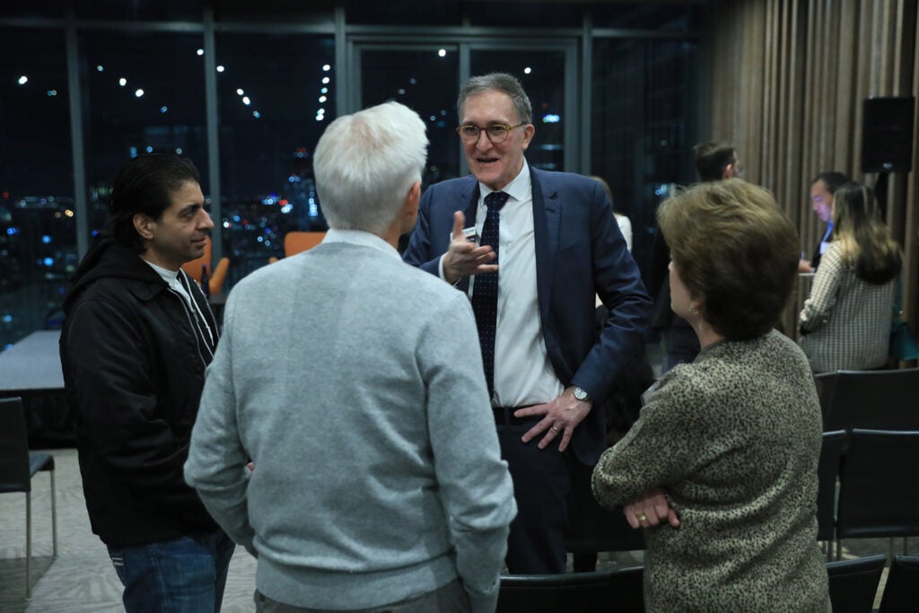 Andrea Baccerelli chats with three people before a speaking event. 