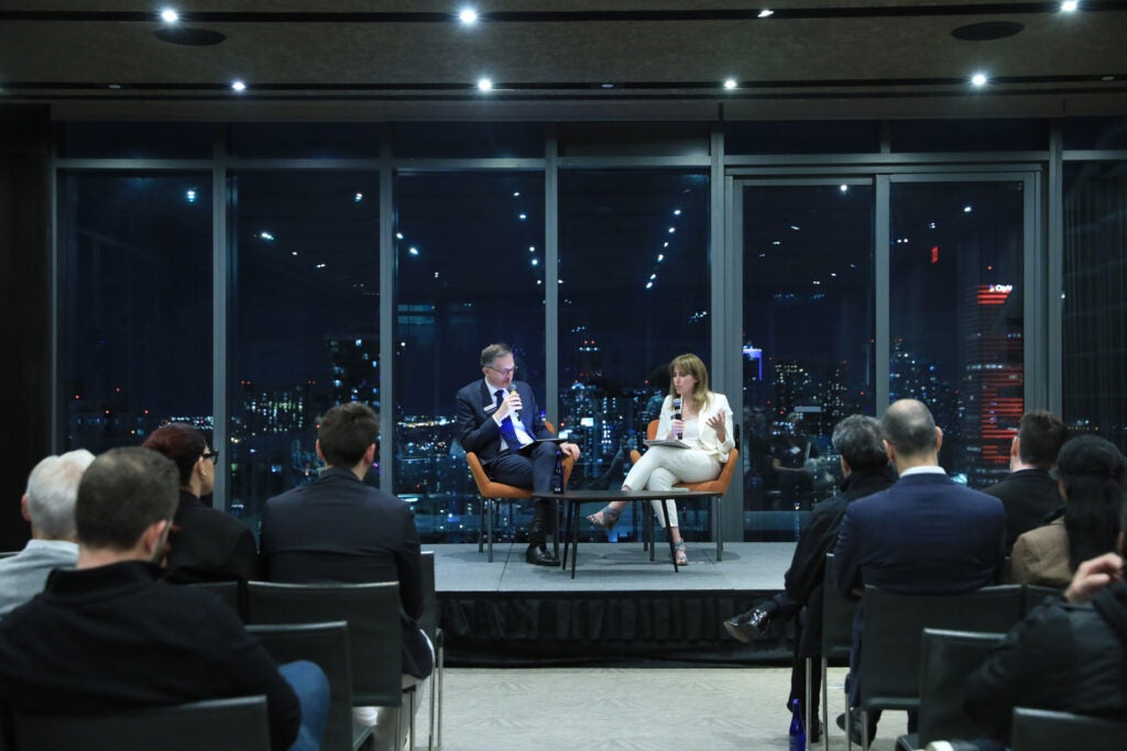 Amanda Yarnell and Andrea Baccerelli in sit on a stage in conversation at a speaking event.