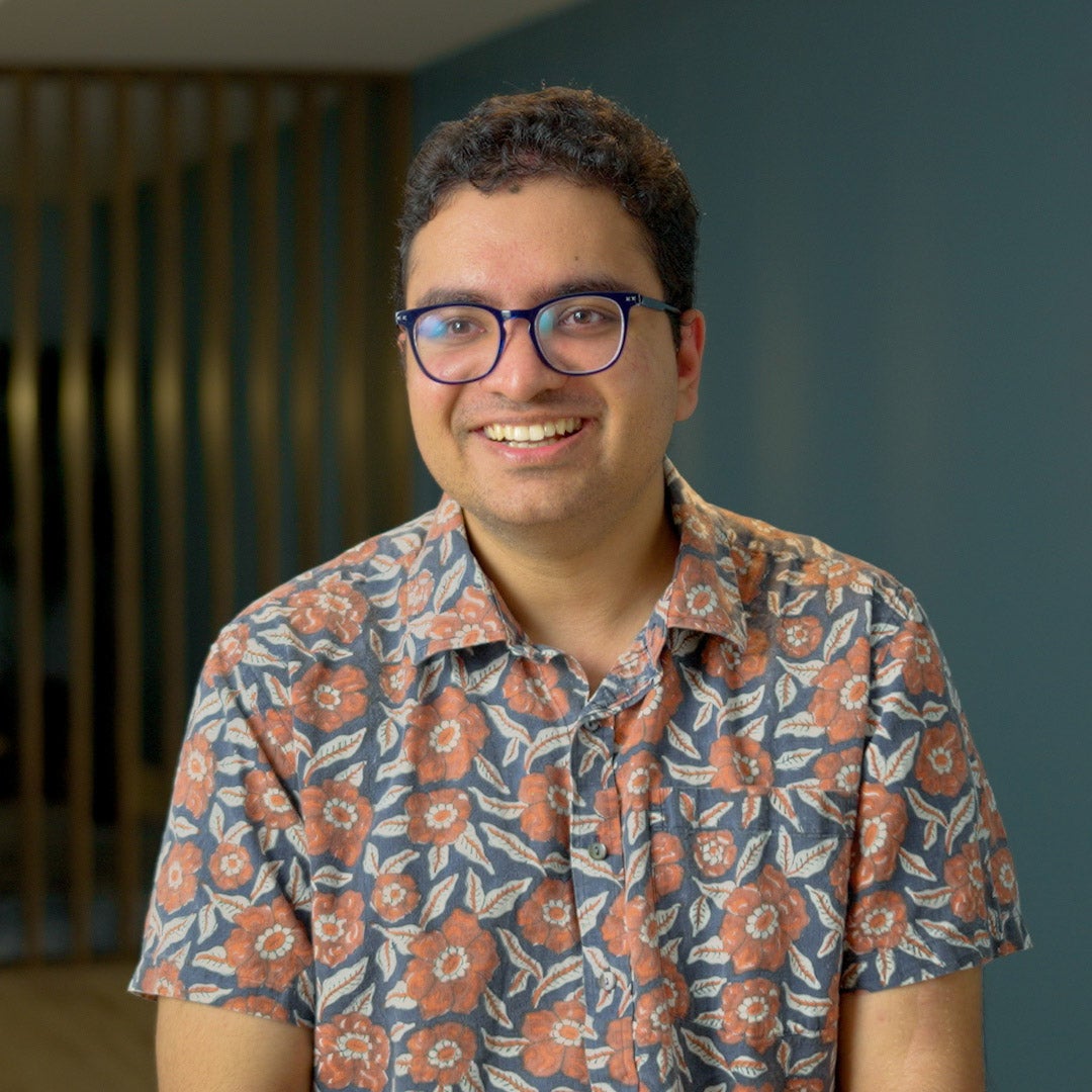 Akshay Narayanan, wearing a floral short-sleeve button-down and dark-rimmed glasses. 